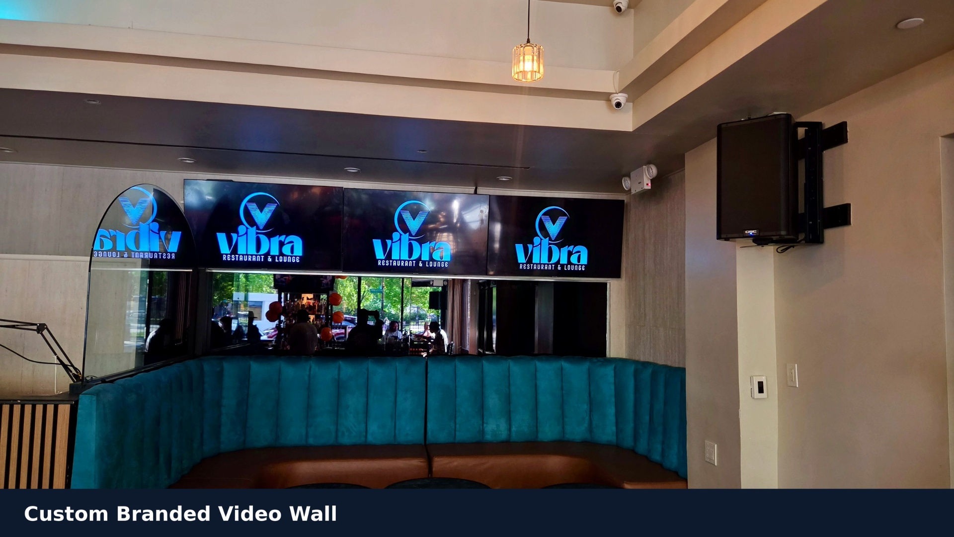 Custom branded video wall displaying the Vibra Restaurant & Lounge logo above teal banquette seating