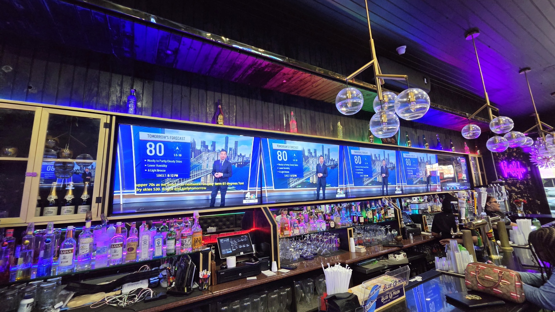 Bar area with multi-screen video distribution and pendant lighting at a restaurant and lounge