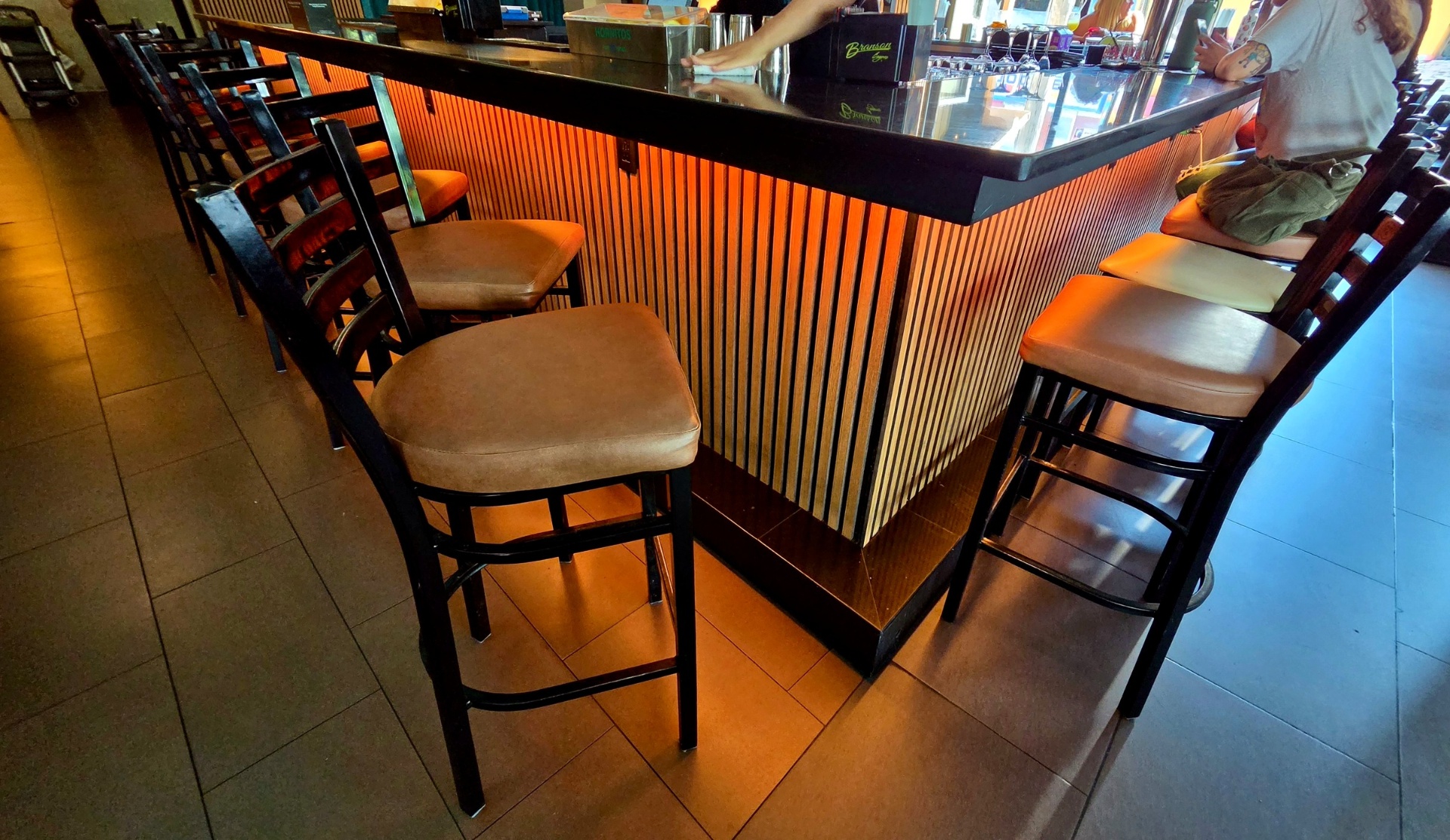 Under-bar LED accent lighting along a wood slat bar front at a restaurant and lounge